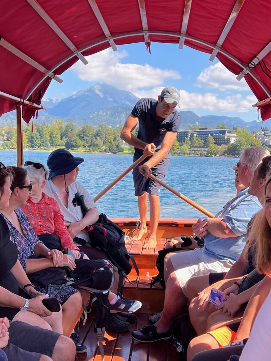 A pletnar rowing a pletna boat across Lake Bled Slovenia