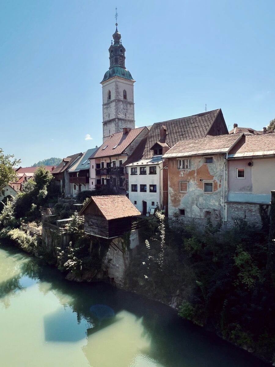 Riverside houses and a church spire in the medieval village of Škofja Loka Slovenia