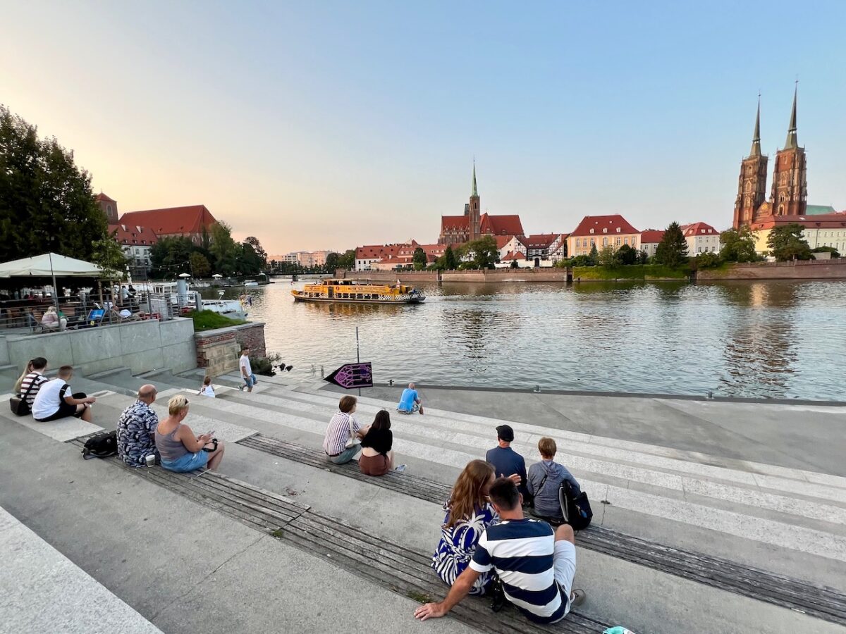 Couples sitting along the Oder River with a view of Cathedral Island