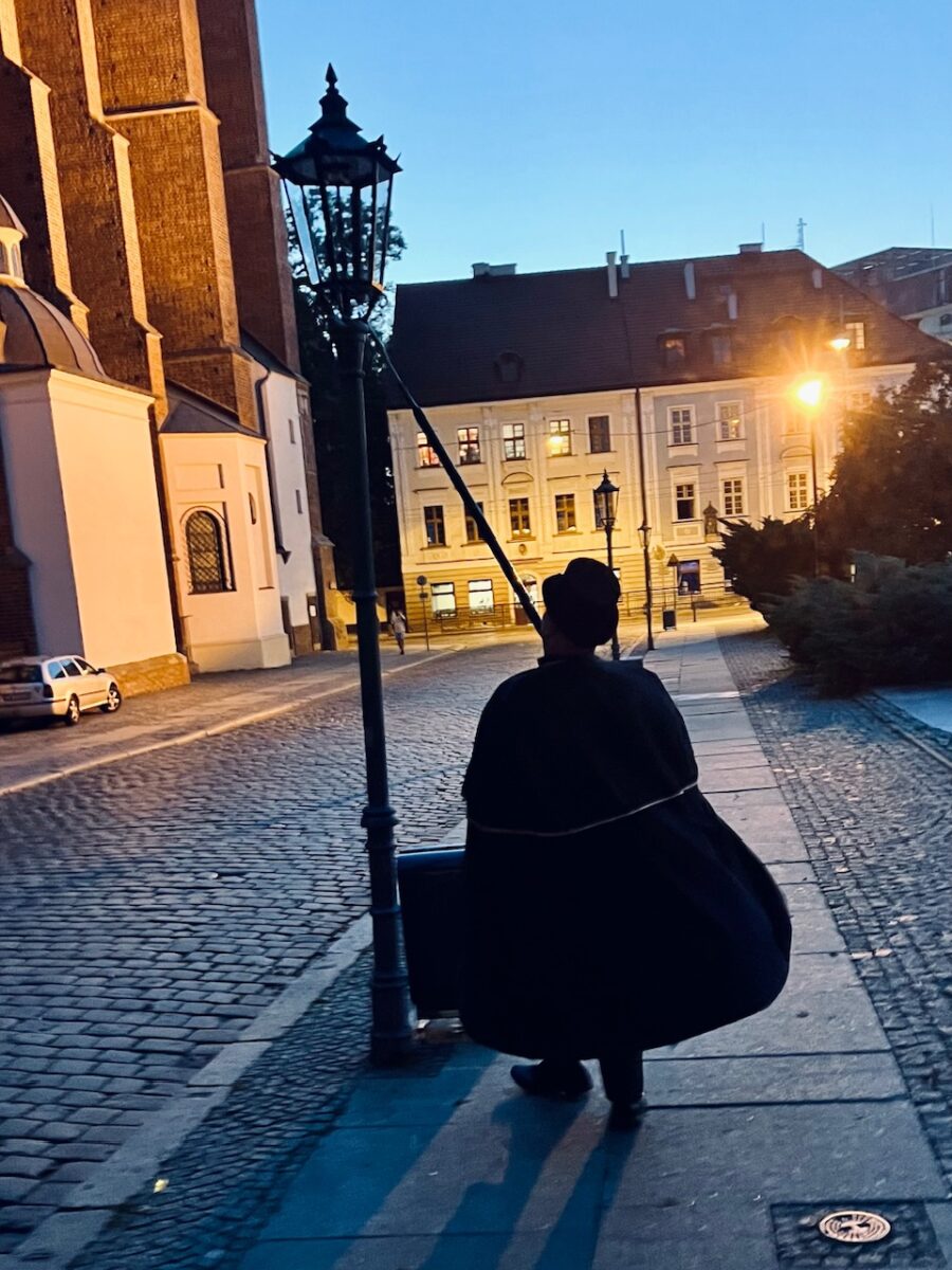 The Lamplighter lighting a street lamp on Cathedral Island in Wroclaw Poland