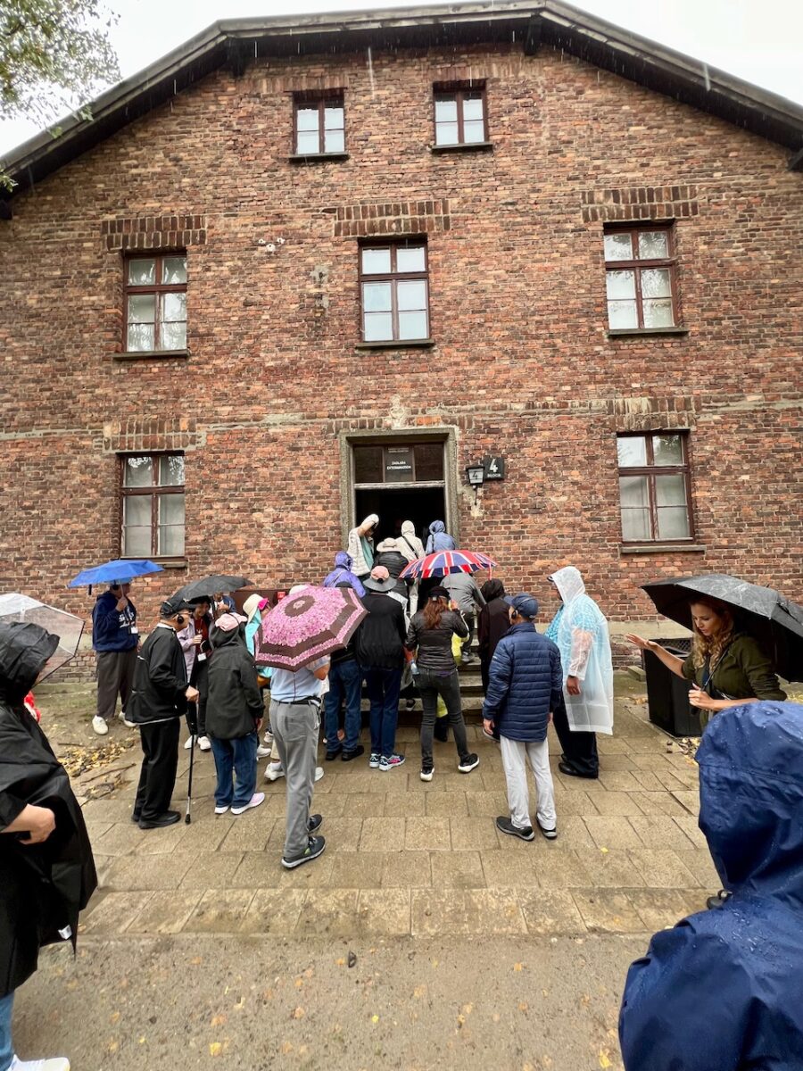 A crowd lines up outside one of the buildings while visiting Auschwitz