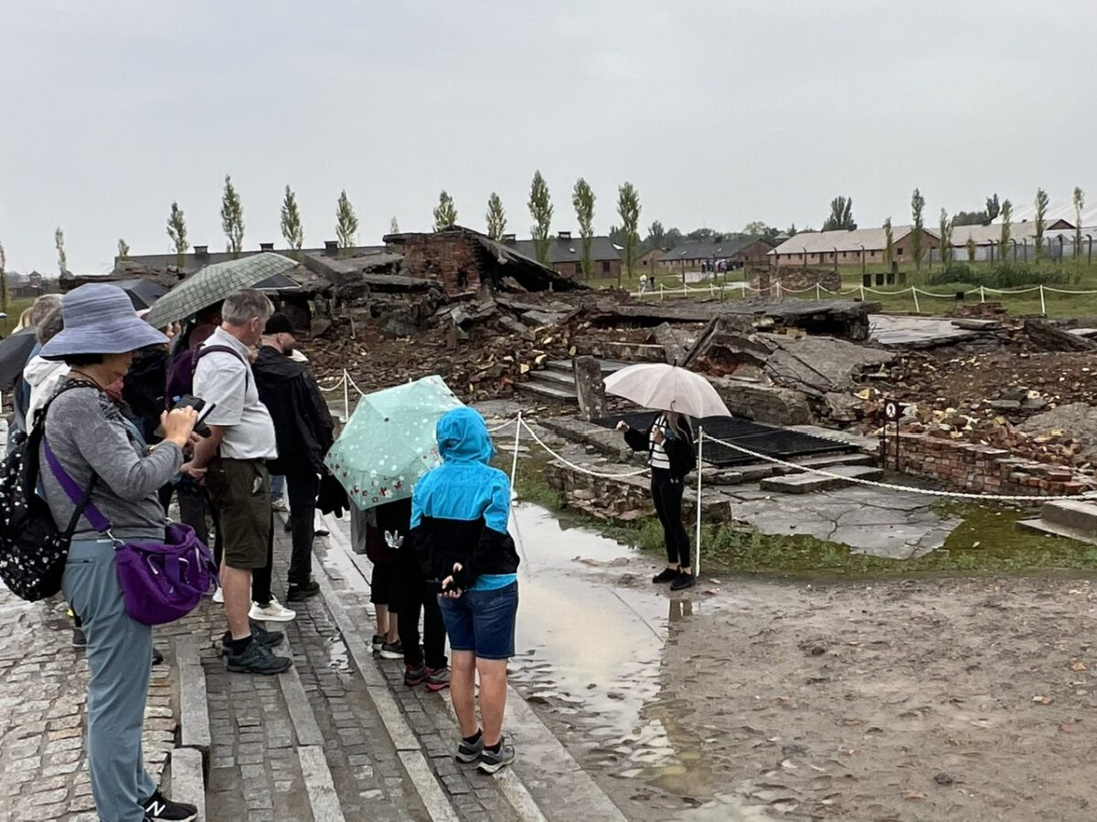 A tour group stands outside the ruins of a gas chamber at Birkenau concentration camp