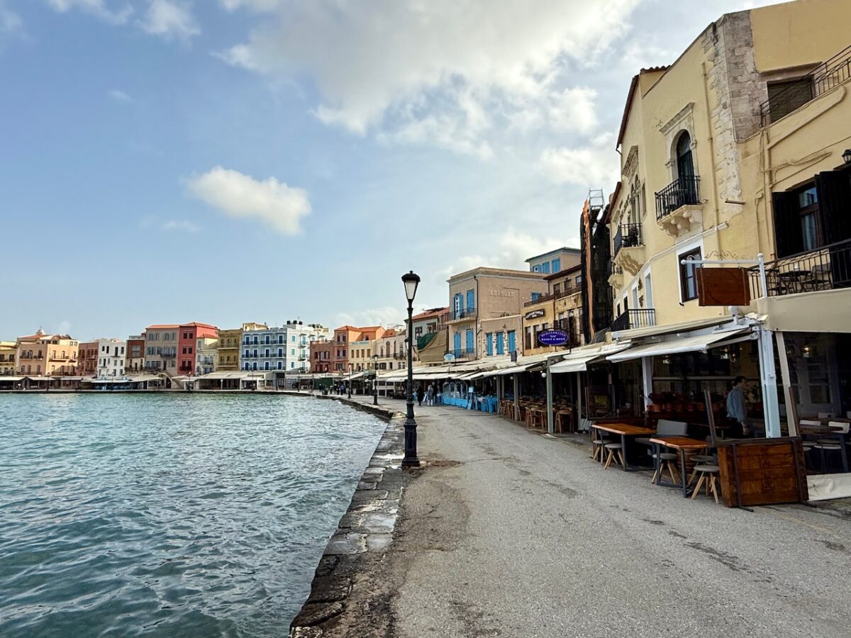 Colorful buildings and restaurants lining the Venetian harbor in Chania Crete. This beautiful harbor may sway you towards Chania if deciding between Heraklion or Chania