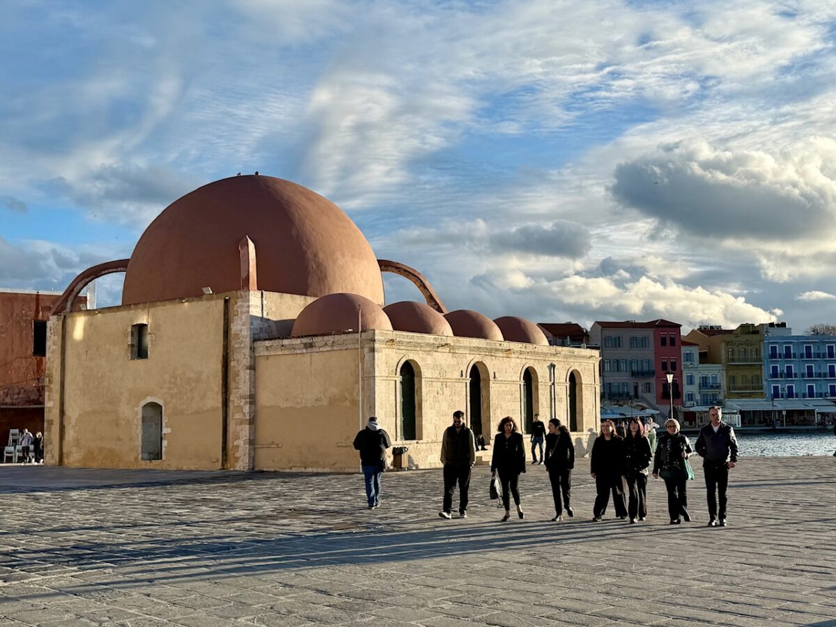 The Küçük Hasan Pasha Mosque in Chania Crete at sunset with a line of passersby. 