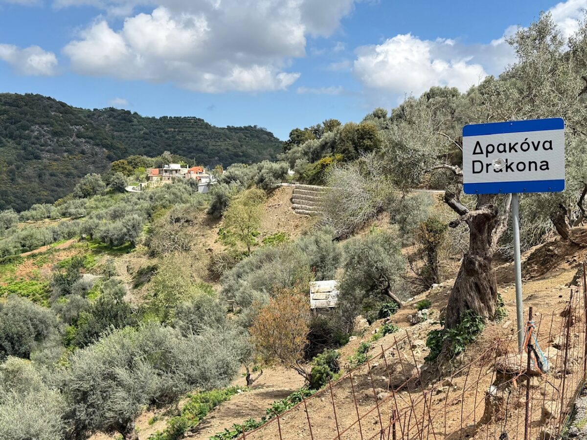Signpost announcing the town of Drakona Crete with Ntounias Farm in the distance