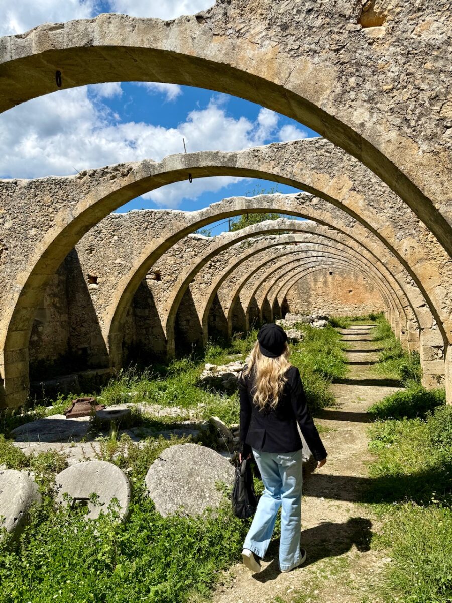A woman walks through the ruins of an olive mill at St George Monastery in Crete