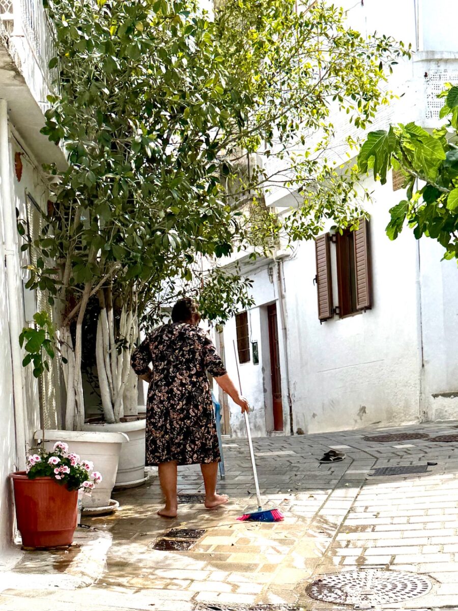 A woman cleaning the entire to her house in an alley in Kritsa Crete