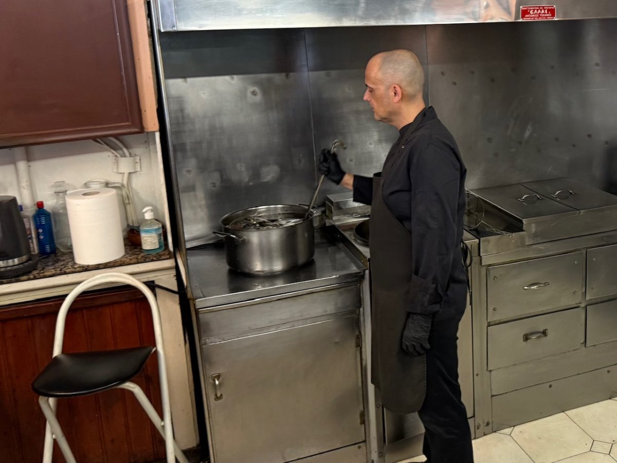 The owner of Loukoumades Ktistakis in Athens  soaking the loukoumades in cold sugar syrup