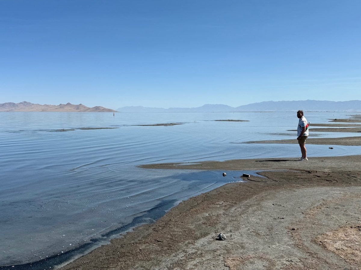A man looks out across the Great Salt Lake from the shoreline near the Great Salt Lake State Park