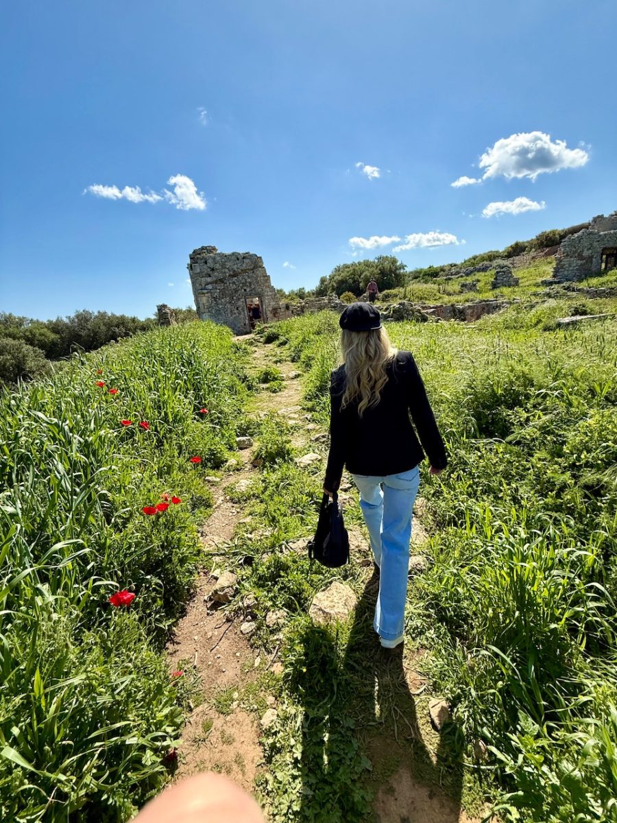 A woman walks toward a the ruins of a Roman Bath House at Ancient Aptera